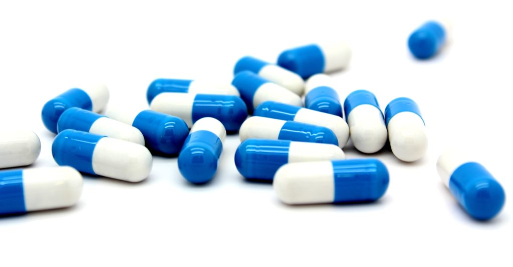 Blue and white pills scattered to show spilled and benefits of SelectCare Adherence Program